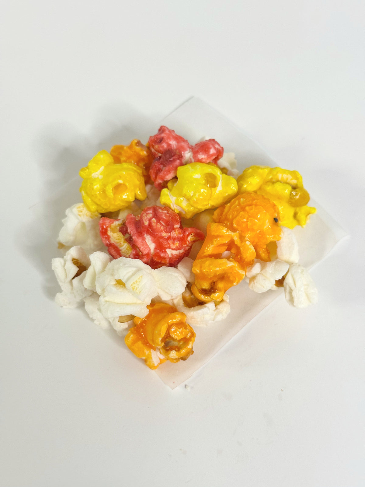 Assorted colored popcorn on a white plate with a white background gourmet popcorn gift bag