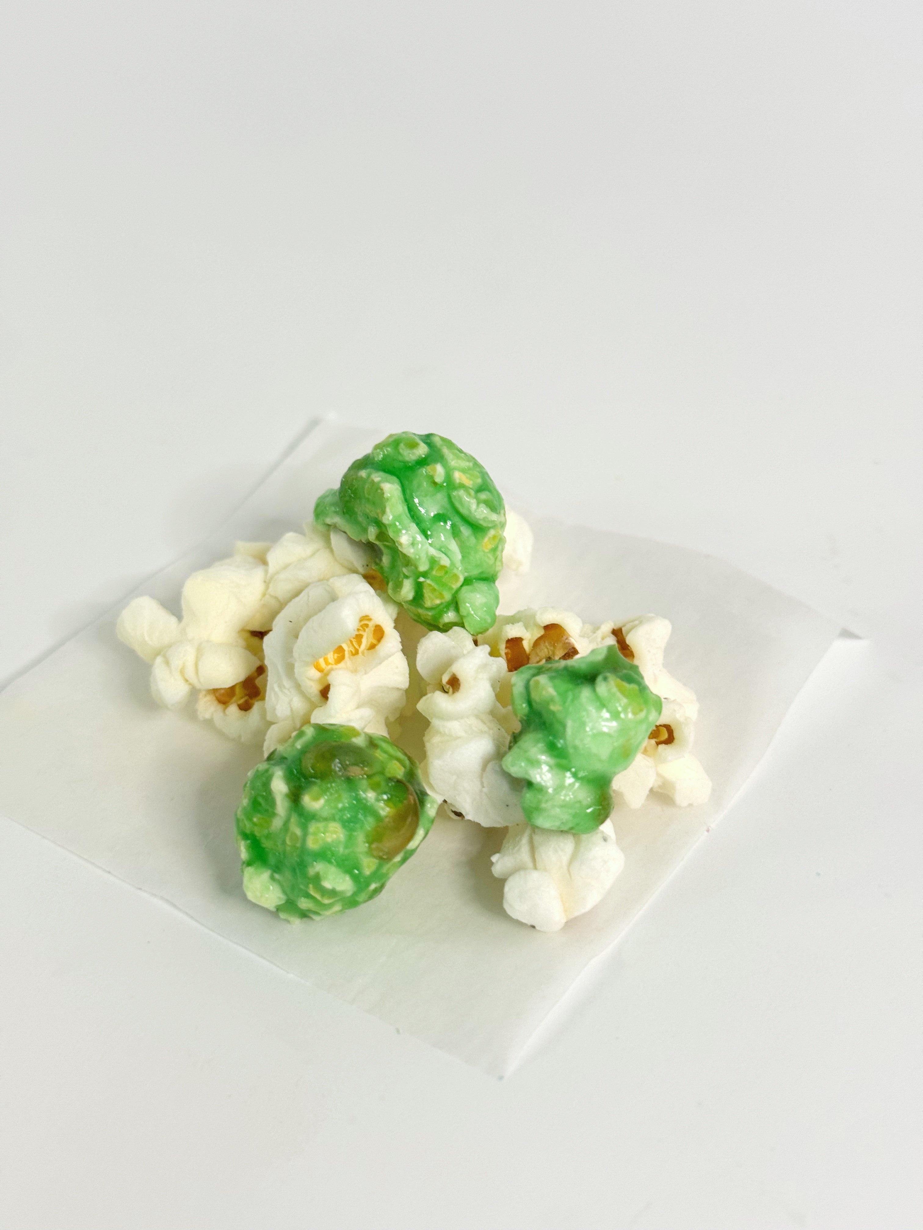 Green and white popcorn on a white plate with a white background
