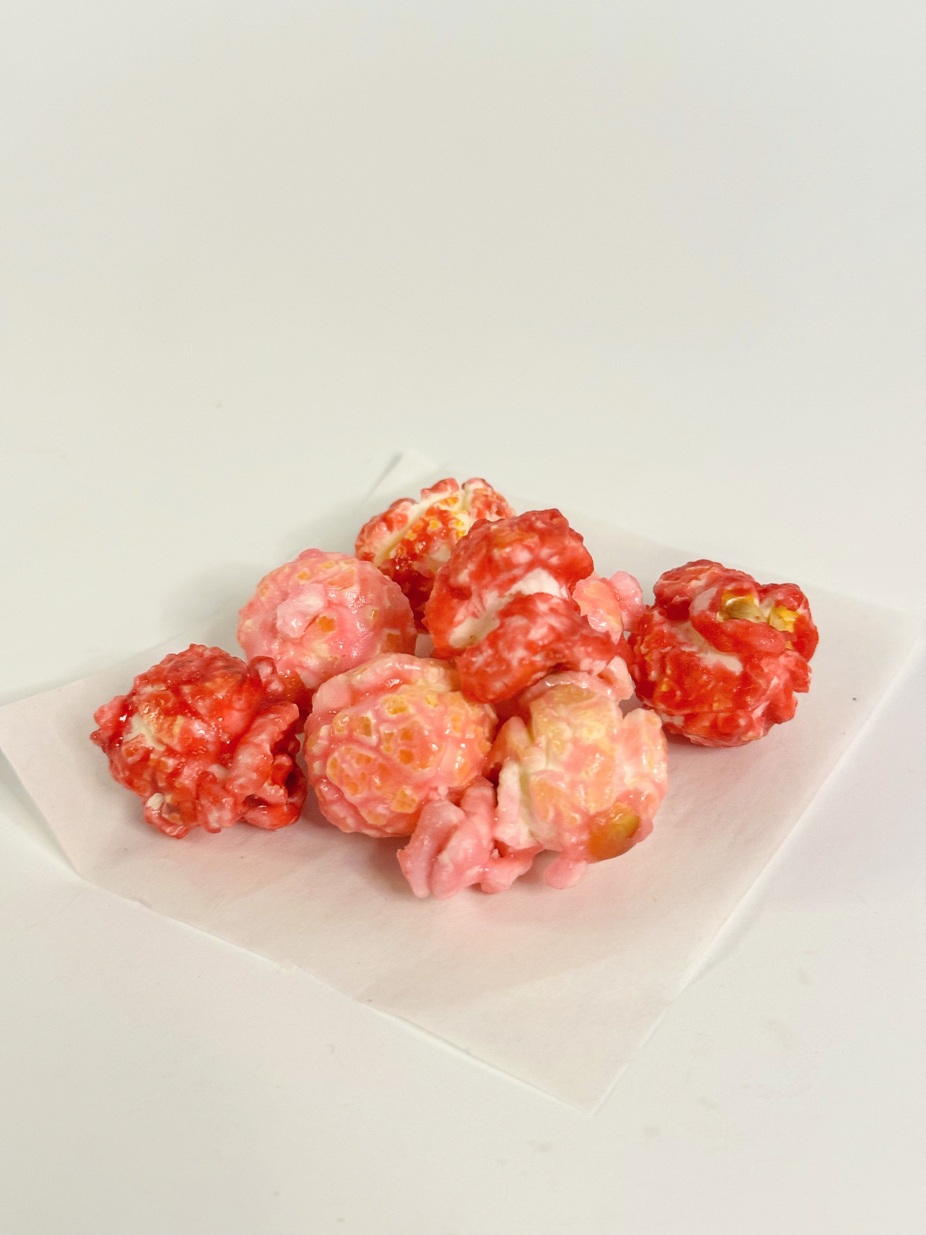 Pink popcorn on a white plate with a white background gourmet popcorn gift bag