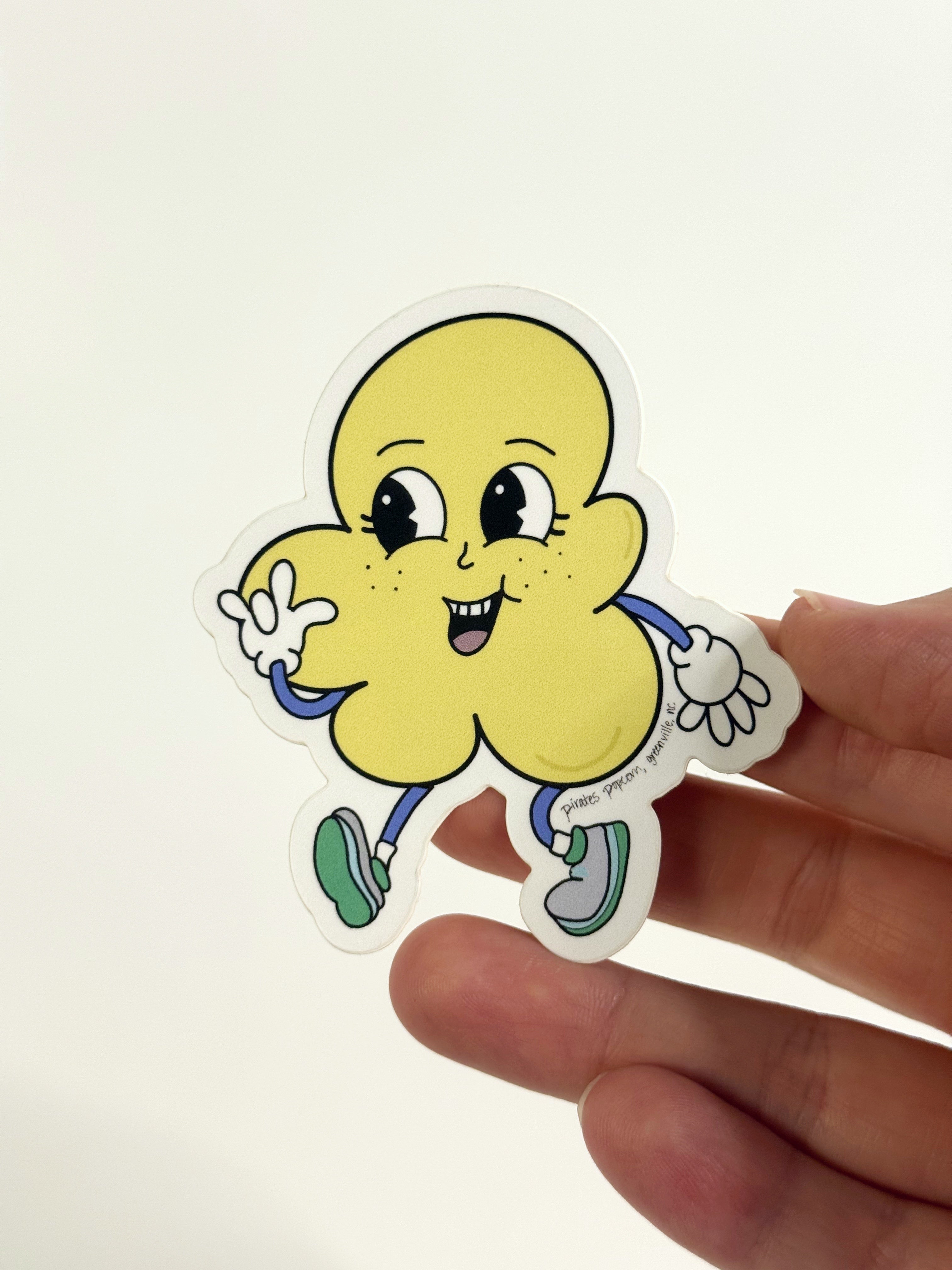 Hand holding a cartoon character sticker with a white background